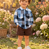 Smiling toddler boy in the Tokabear reversible muslin shirt in a sunlit garden